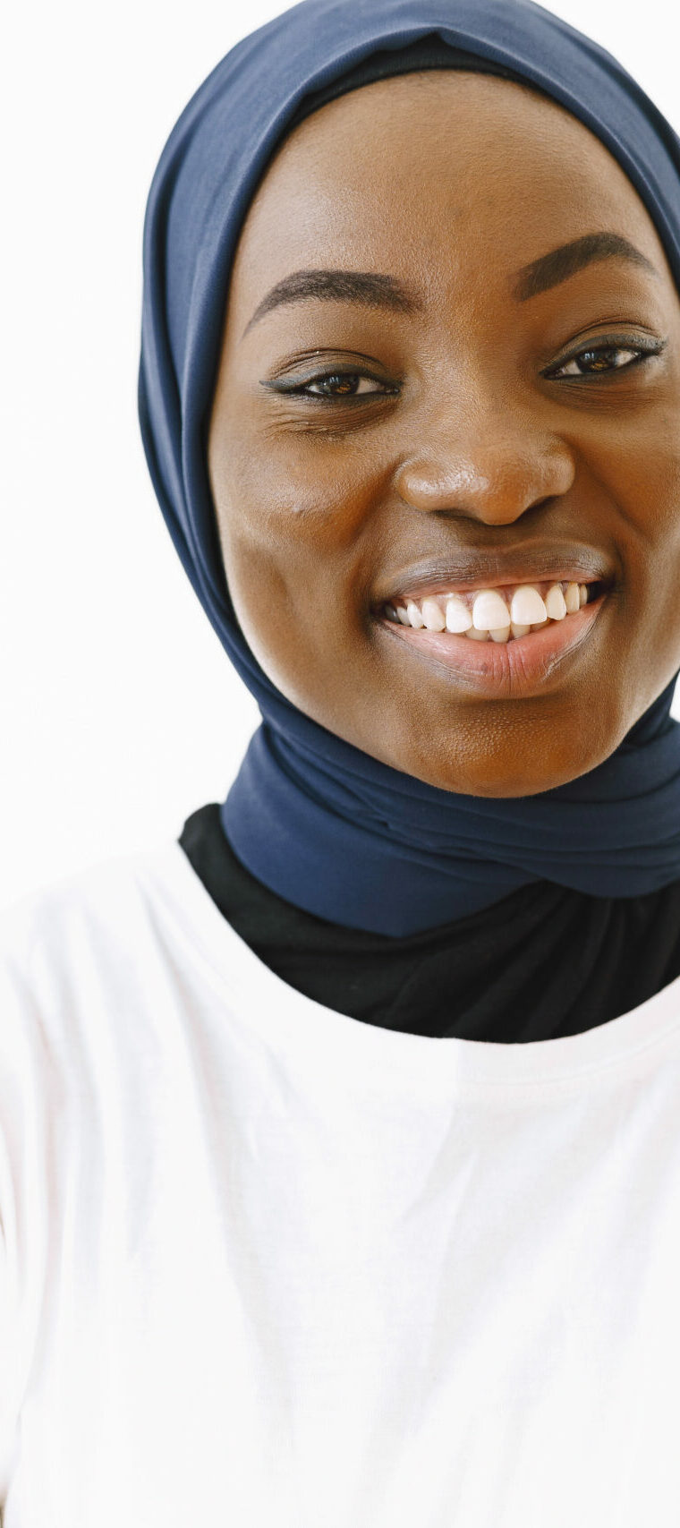 Headshot of lovely satisfied religious Muslim woman with gentle smile, dark healthy skin, wears scarf on head. Isolated over white background.